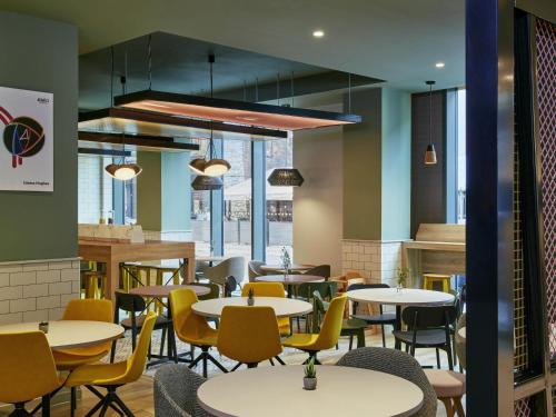 un restaurant avec des tables blanches et des chaises jaunes dans l'établissement Aparthotel Adagio Glasgow Central, à Glasgow