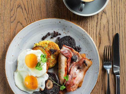 a plate of breakfast food with eggs and bacon at Fable Terrace Downs Resort by MGallery in Windwhistle