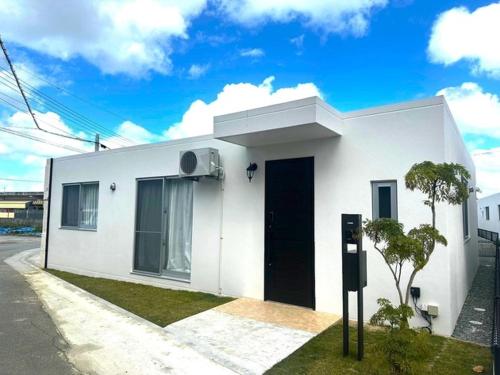 a white house with a black door on a street at Miyakojima - House - Vacation STAY 20446 in Hirara