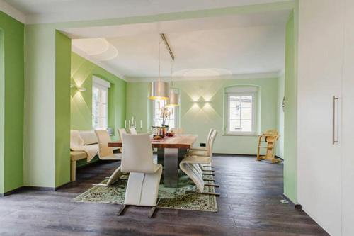 comedor con paredes verdes, mesa y sillas en Villa Johner en Bayreuth