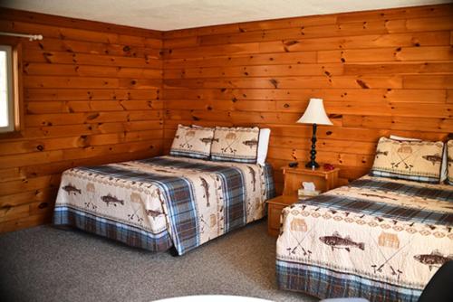 two beds in a room with wooden walls at Smith's Colonial Motel in Hancock