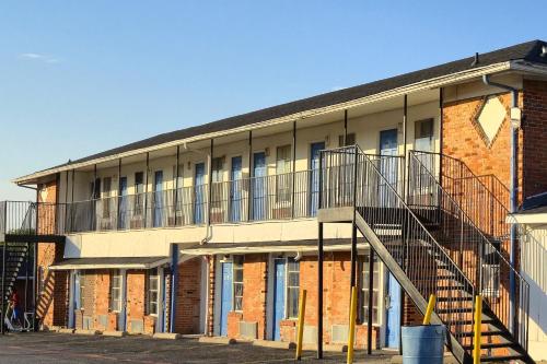 a brick building with a staircase in front of it at Cole Manor Motel By OYO Love Field Market Center in Dallas