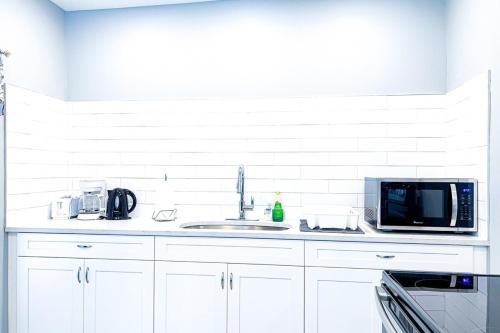 a white kitchen with a microwave and a sink at Group Friendly 6BR Near Aquarium & Niagara Falls in Niagara Falls