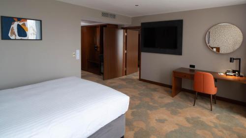 a bedroom with a bed and a desk and a television at Holiday Inn Bristol City Centre by IHG in Bristol