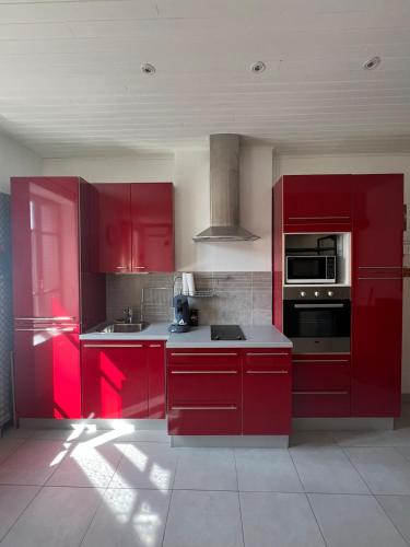 een rode keuken met rode kasten en apparaten bij Studio centre ville in Bourgoin