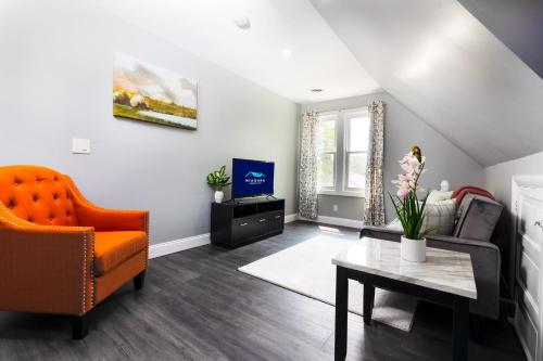 a living room with an orange chair and a couch at Cozy Micro apartment, Minutes from Falls in Niagara Falls