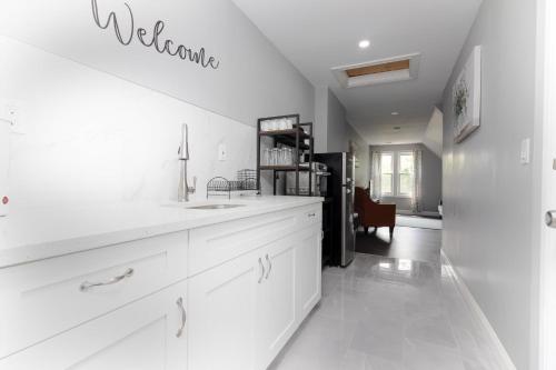 a white kitchen with a sink and a counter at Cozy Micro apartment, Minutes from Falls in Niagara Falls