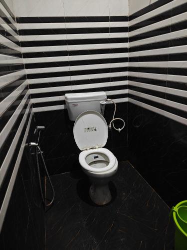 a bathroom with a toilet with black and white stripes at Krishna guest House luxury stay in Ayodhya - 600 meter away from ram mandir in Ayodhya