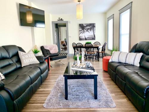 a living room with black leather couches and a table at 5BR Niagara Getaway Prime Location-Sleeps 10 in Niagara Falls