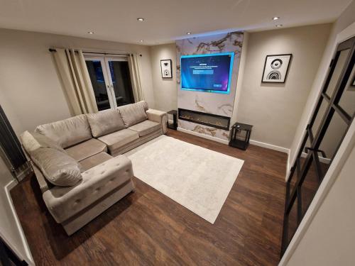 a living room with a couch and a flat screen tv at Edinburgh West Luxury 5 Bedroom Home in Edinburgh