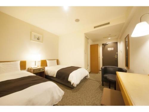 a hotel room with two beds and a desk at Smile Hotel Tokyo Ayase Ekimae - Vacation STAY 62867v in Tokyo