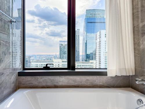 a bath tub in a bathroom with a window at Luxury Downtown Bangkok 2BR 2BA Sky Pool Gym 5MIN Walk to Siam Paragon in Pratunam