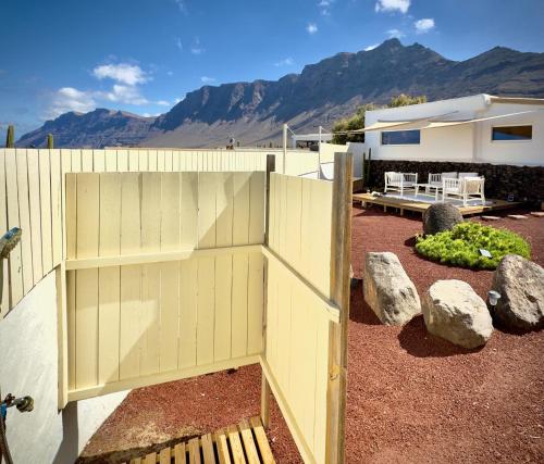ein Holzzaun in einem Hof mit Bergen im Hintergrund in der Unterkunft Apartamento vintage en Playa Famara in Famara