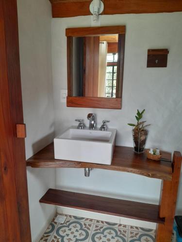 a bathroom with a white sink and a mirror at Pousada Canto da Lua in Carrancas