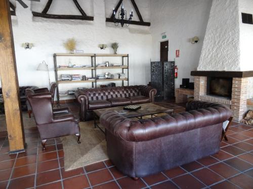 a living room with leather couches and a fireplace at Hotel Cortijo del Marqués in Albolote