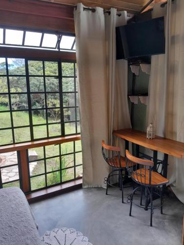 a room with a table and chairs and windows at Pousada Canto da Lua in Carrancas