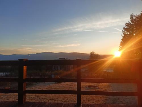 a sunset over a fence with the sun setting at Domek w górach Łubinowa 6 in Międzylesie