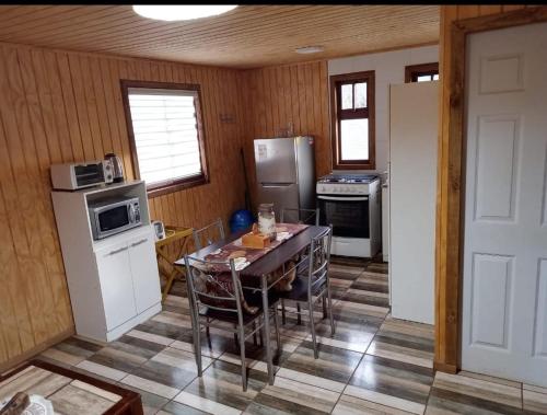una cocina con una mesa y un refrigerador en Casa amoblada con portón eléctrico, en Estación Roblería