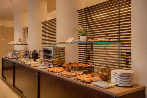 a bakery with a counter with pastries and bread at NH Linate in Peschiera Borromeo