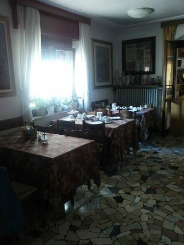 a dining room with tables and a window and a room with a unintention at Hotel Piol in Limana