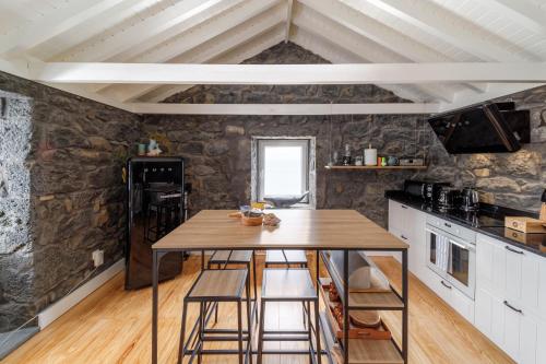 - une cuisine avec une table en bois et un mur en pierre dans l'établissement BIOMA Adega - Escala Gourmet, à Calheta de Nesquim
