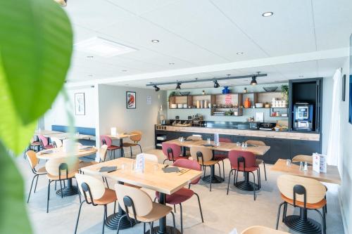 un restaurant avec des tables et des chaises et une cuisine dans l'établissement Ibis Orleans La Chapelle Saint Mesmin, à La Chapelle-Saint-Mesmin