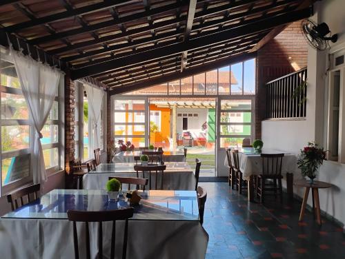 a dining room with tables and chairs and windows at POUSADA VILA DE ATALAIA OFlCIAL in Canavieiras