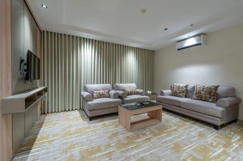 a living room with two couches and a tv at السهم الذهبي للشقق المخدومة in Taif