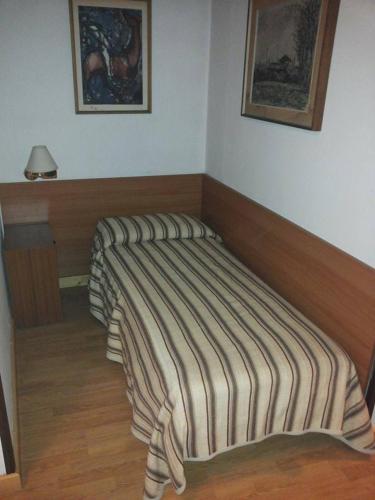 a bed with a striped blanket in a room at Hotel Piol in Limana