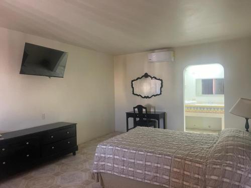 een slaapkamer met een bed en een tv aan de muur bij Hotel Colonial 