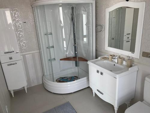 a white bathroom with a shower and a sink at Коттедж - Вилла in Chok-Tal