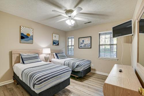 a bedroom with two beds and a flat screen tv at Pawleys Island Condo with Screened Porch and Golfing! in Pawleys Island