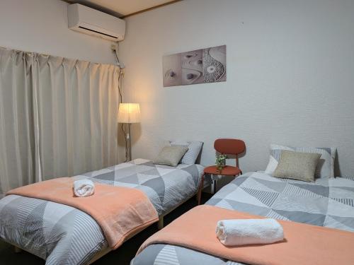 ein Zimmer mit zwei Betten und einem Stuhl in der Unterkunft Apartment Primeira Classe Room 1A - Vacation STAY 54531v in Imaichi