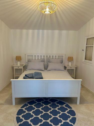 1 dormitorio con cama blanca y alfombra azul en La Cabane du Soleil, en Beausoleil