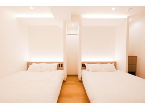 two beds in a room with white walls and wooden floors at HOTEL ALL IN Kumamoto - Vacation STAY 55117v in Hanabatachō