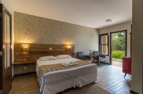 a bedroom with a large bed and a room with a table at Pousada Vila Tamarindo Eco Lodge in Florianópolis