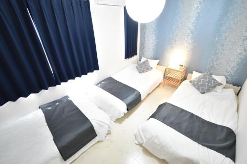 three beds in a room with blue curtains at Kapalua East-Kapalua West - Vacation STAY 20388 in Tokyo