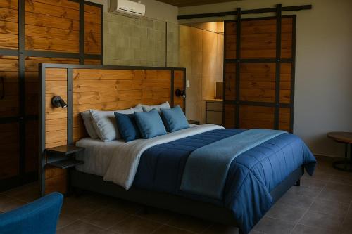a bedroom with a large bed with blue pillows at Mahuida Lodge Valle de Uco in Colonia Las Rosas