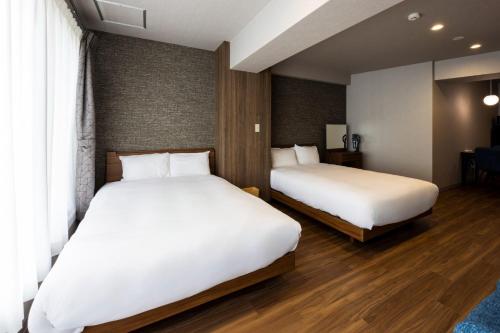 zwei Betten in einem Hotelzimmer mit weißen Laken in der Unterkunft AMP FLAT ARCBLISS 2B - Vacation STAY 57408v in Chikushino