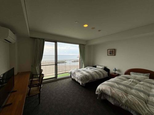 een hotelkamer met twee bedden en een groot raam bij Ocean View Mt, Kaimondake - Vacation STAY 58439v in Oka-chiyogamizu