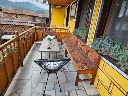 a wooden bench on a balcony with a table at Hotel Rai in Koprivshtitsa