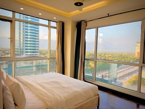 a bedroom with a bed and a large window at High Rise Presidential Suite in Elysium Opp Centaurus in Islamabad