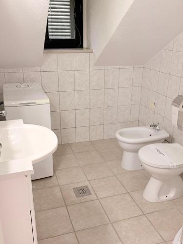 a white bathroom with a toilet and a sink at Humac Vero Apartments in Donji Humac