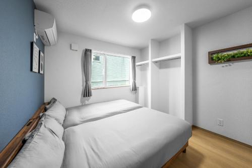 a white bedroom with a bed and a window at Charmant House III - Vacation STAY 20376 in Minamifurano