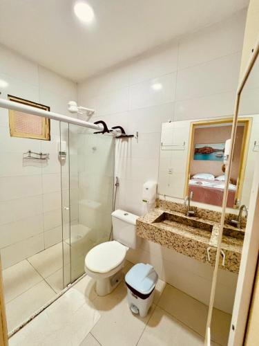 a bathroom with a toilet and a glass shower at Pousada Lampião Rio in Piranhas