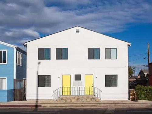 a white house with yellow doors on a street at Sunny Studio in the Heart of Venice - A in Los Angeles