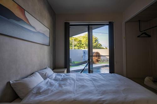 une chambre avec un lit et une grande fenêtre dans l'établissement SANA Izu Omuroyama -Pool Villa- - Vacation STAY 61808v, à Futo