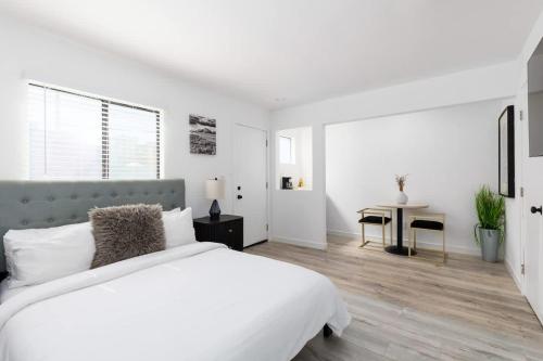 a white bedroom with a large bed and a table at Sunny Studio in the Heart of Venice - B in Los Angeles