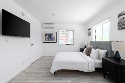 a white bedroom with a bed and a flat screen tv at Sunny Studio in the Heart of Venice - B in Los Angeles