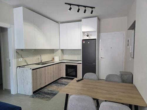 a kitchen with a wooden table and a black refrigerator at Mira Apartment in Tirana